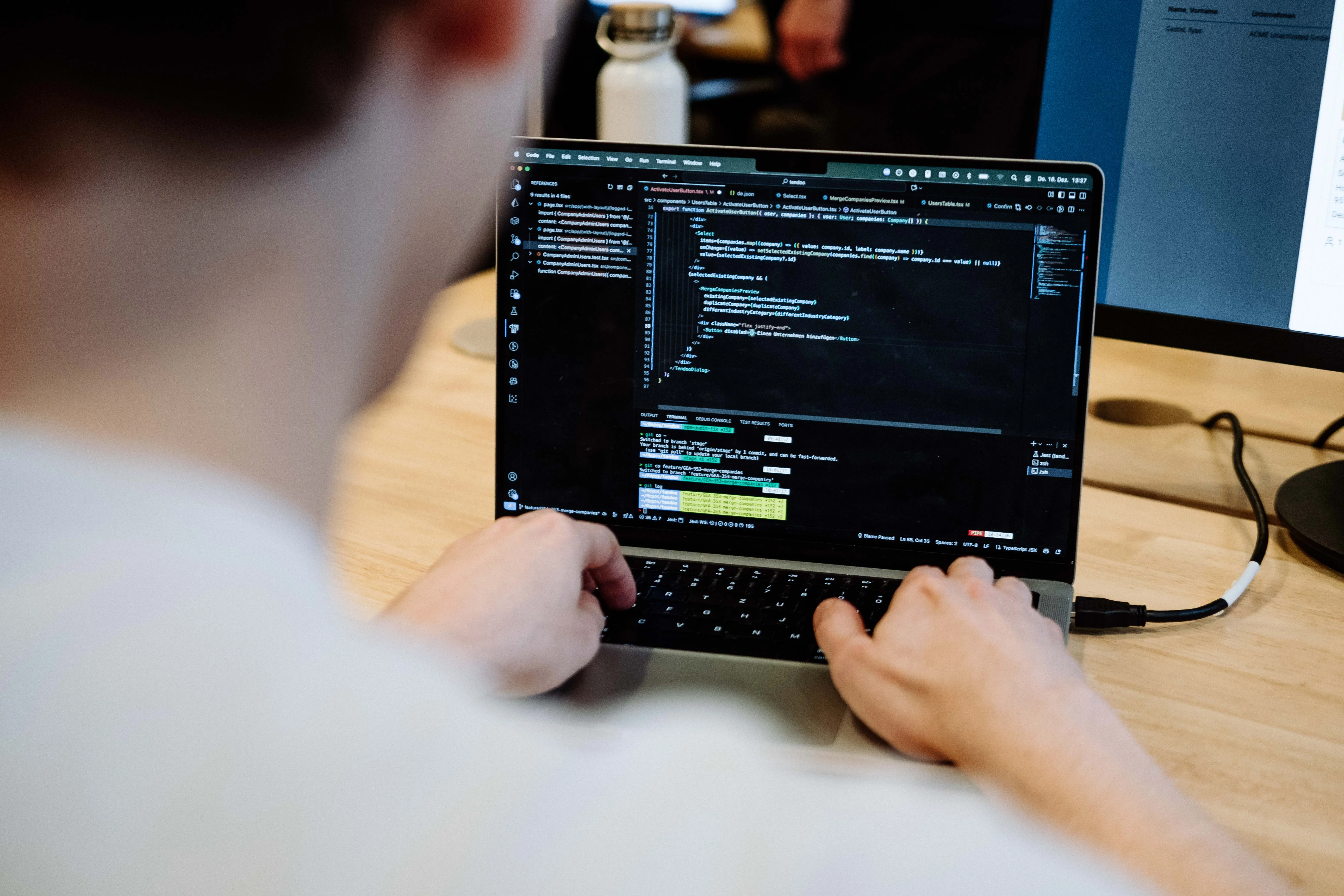 Blick über die Schulter auf einen Bildschirm mit Programmcode.