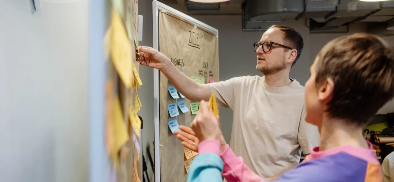 Person steht an einem Whiteboard mit Notizzetteln in einem Workshop.