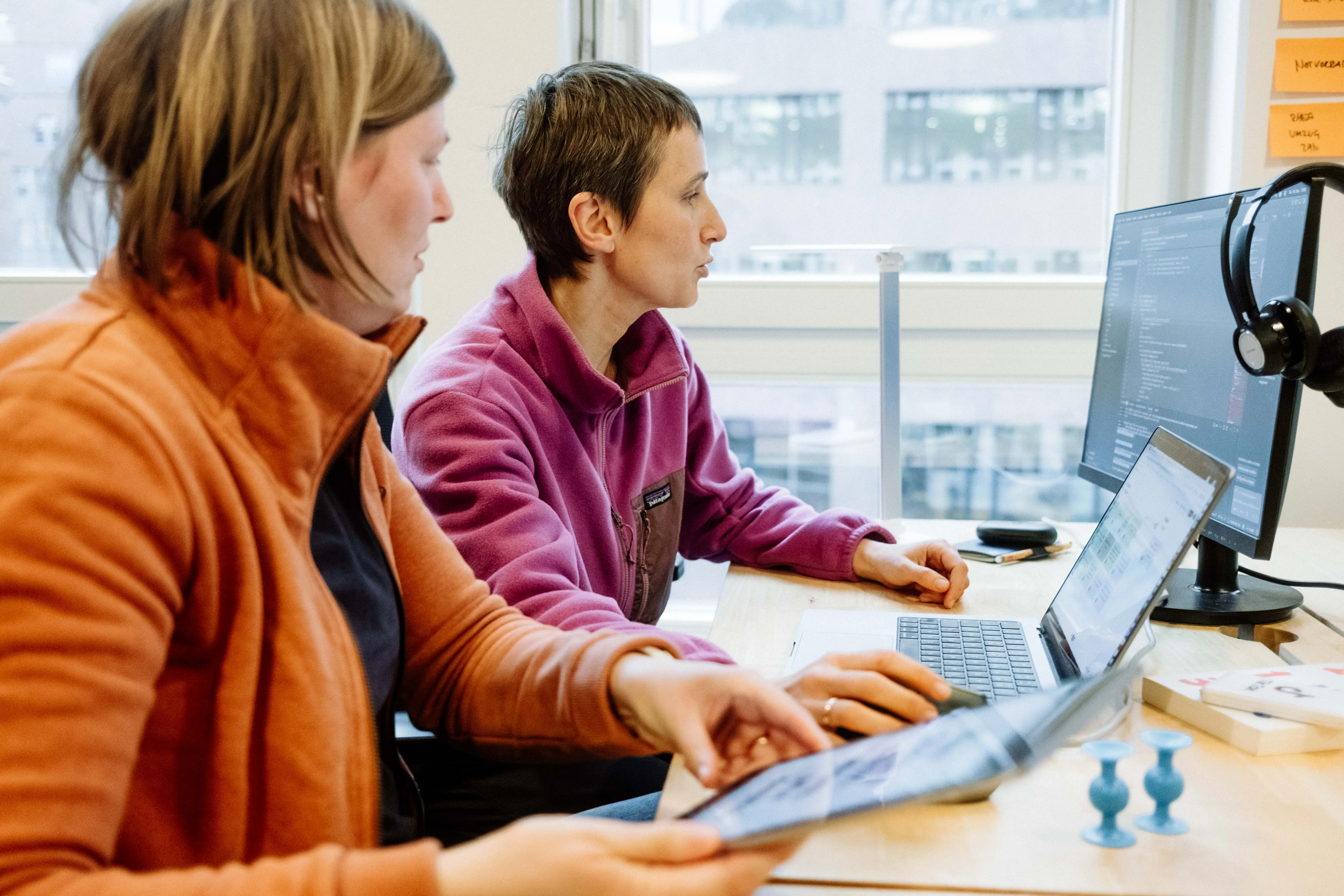 Zwei Personen arbeiten gemeinsam an Code an einem Bildschirm.